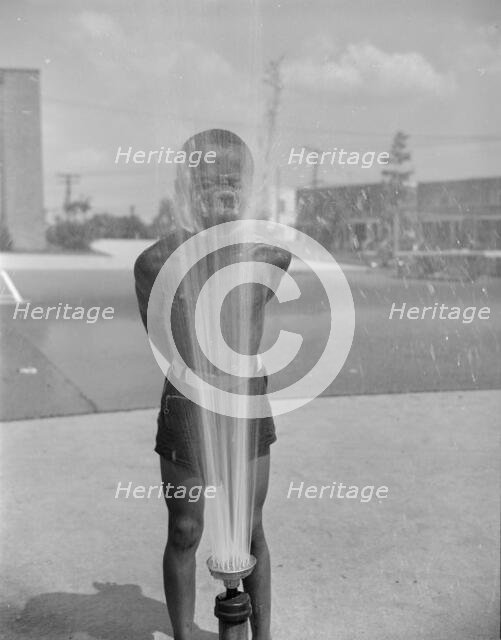 Playing in the community sprayer, Frederick Douglass housing project, Anacostia, D.C., 1942. Creator: Gordon Parks.