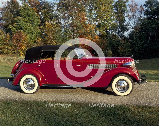 A 1936 Auburn 852 car on a gravel driveway in the autumn sunlight. Artist: Unknown