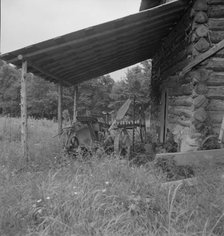 Farm machinery drawn under cover of old tobacco barn, Person County, North Carolina, 1939. Creator: Dorothea Lange.