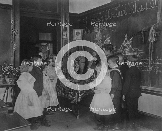 Teacher showing students Native American handicrafts at a school in Washington, D.C., (1899?). Creator: Frances Benjamin Johnston.