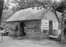 Double log cabin of Negro share tenants who raise tobacco, Person County, North Carolina, 1939. Creator: Dorothea Lange.
