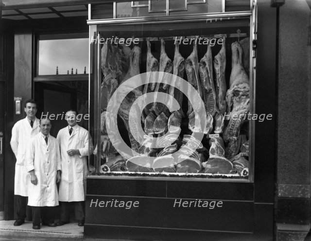 Butchers standing next to their shop window display, South Yorkshire, 1955.  Artist: Michael Walters