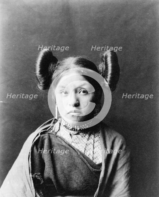 Gobuguoy, Walpi girl, half-length portrait, facing front, hair tied in swirls on sides of..., c1900. Creator: Edward Sheriff Curtis.