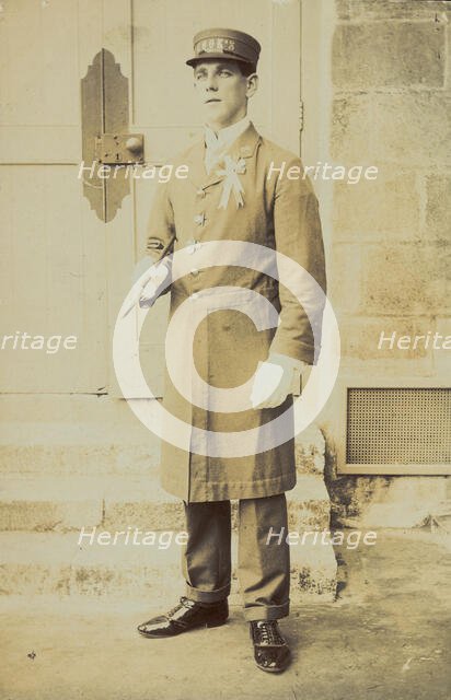 A man dressed wearing a long coat and a hat bearing the word "Cook"...(1910-1919?). Creator: Unknown.