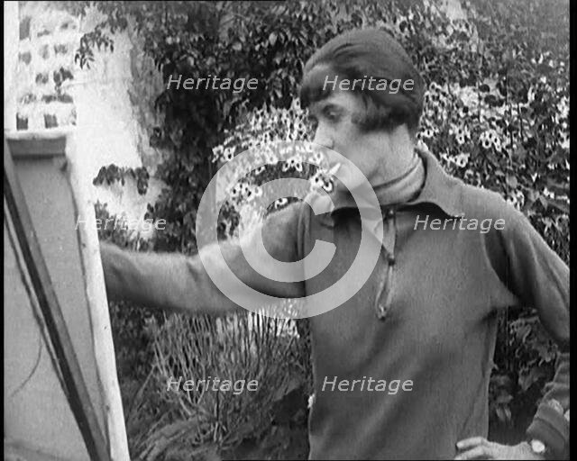 A Female Civilian Painting at an Easel Outdoors Smoking a Cigarette, 1920. Creator: British Pathe Ltd.