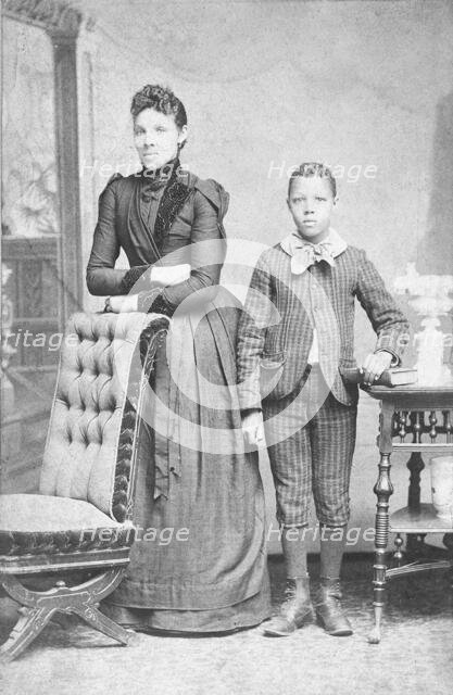 Unidentified standing figures: woman, her folded arms leaning on back of chair..., c1890. Creator: J. N. Wilson.
