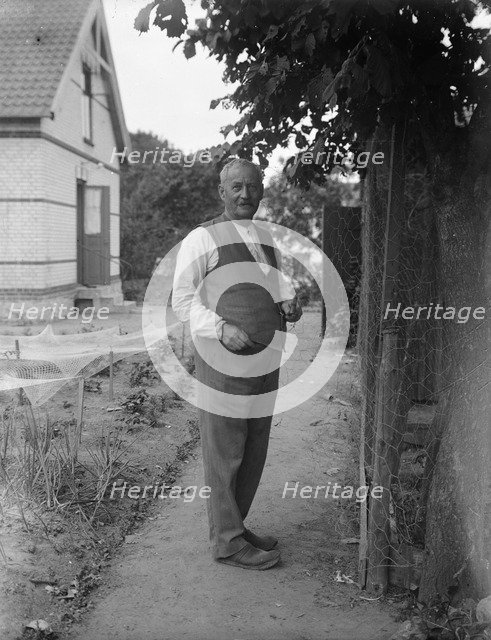 An elderly man repairing chicken wire in his garden, Flyinge, Sweden, 1920s. Artist: Unknown