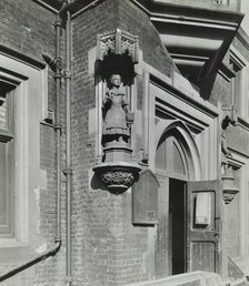 Statue of a girl scholar beside the door, Hamlet of Ratcliff Schools, Stepney, London, 1945. Artist: Unknown.