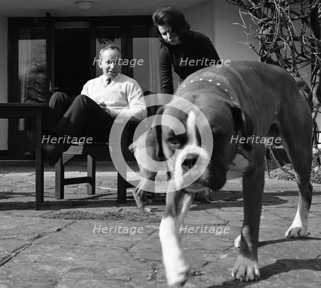John Surtees relaxes at home with his wife and pet dogs in 1966. Creator: Unknown.