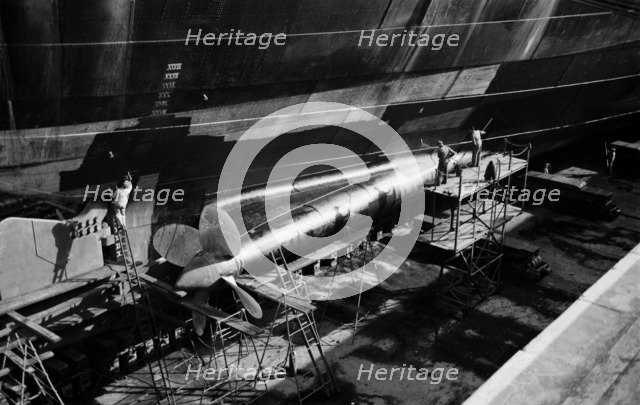 Men clean and paint the hull of a ship in the New Dry Dock, Tilbury Docks, Tilbury, c1945-c1965. Artist: SW Rawlings