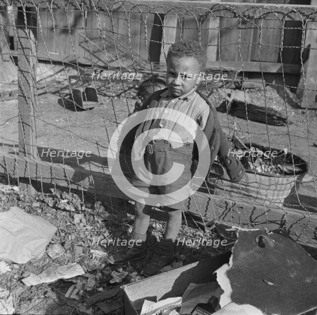 Boy playing in the backyard of his home, Washington (southwest section), D.C., 1942. Creator: Gordon Parks.