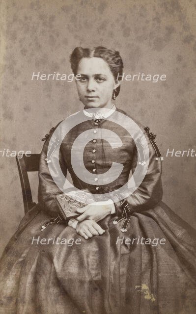 Business card, studio portrait of woman holding a photo album. (c1880s) Creator: Karolina Christianson.