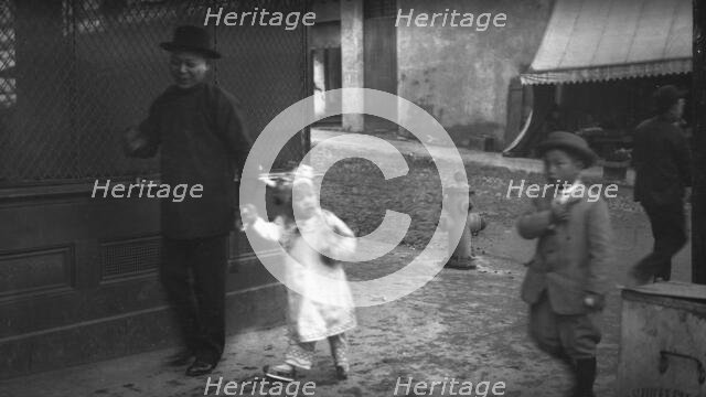 Man and a young child walking down a street, Chinatown, San Francisco, between 1896 and 1906. Creator: Arnold Genthe.
