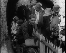 A Model Train Passes Through a Tunnel As a Crowd of People Watch from Behind a Fence, 1924. Creator: British Pathe Ltd.