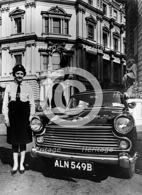 Female chauffeur standing by a 1964 Morris Oxford, 1964. Artist: Unknown