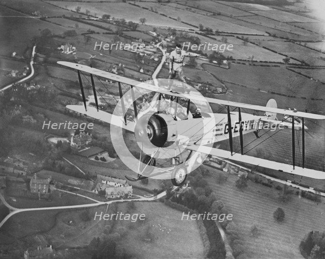 Man wing walking on an Avro 504 biplane without a harness, 20th century. Artist: Aerofilms.