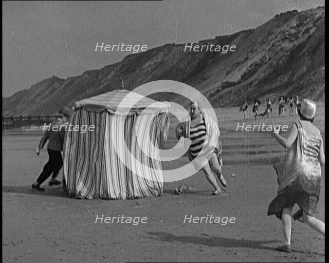A Male Actor With a Moustache and Bowler Hat Being Chased Around a Changing Tent On a Beach...,1920s Creator: British Pathe Ltd.