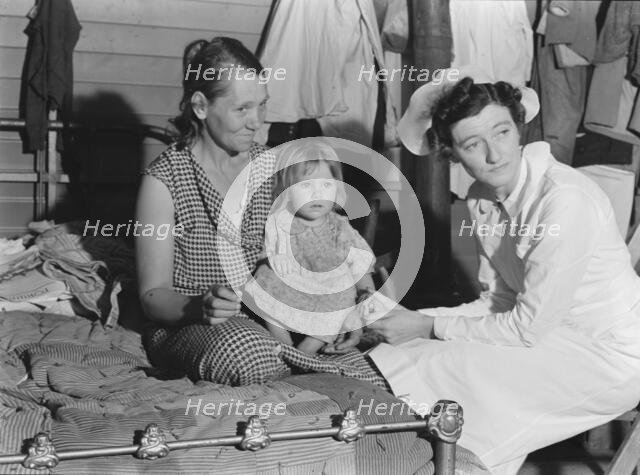 Nurse attending sick baby, FSA camp, Farmersville, Tulare County, California, 1939. Creator: Dorothea Lange.