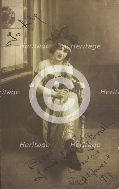 A man in drag (Charlie) sits face-on, wearing detailed costume, with a window painted..., 1919. Creator: Unknown.