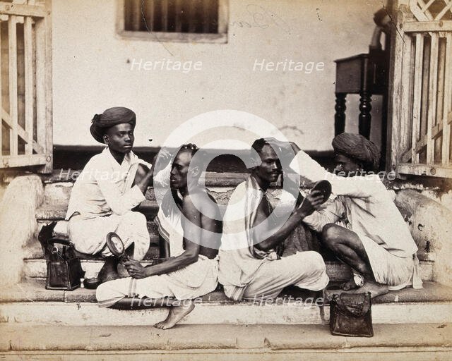 Two Indian barbers wearing turbans shaving the heads of two Indian men..., c1900s. Creator: Unknown.