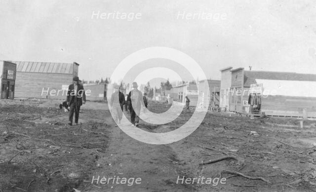 Three men walking down a dirt road, through town, between c1900 and 1916. Creator: Unknown.
