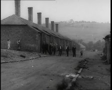 Male Civilians Standing in the Streets Outside of Their Houses, 1926. Creator: British Pathe Ltd.