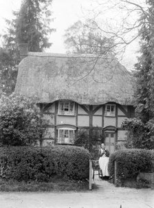 Woman holding her cat at the gate of her cottage, Uffington, Oxfordshire, c1916. Artist: FW Ault