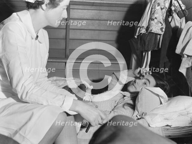 Nurse attending sick migrant woman, FSA camp, Farmersville, Tulare County, California, 1939. Creator: Dorothea Lange.