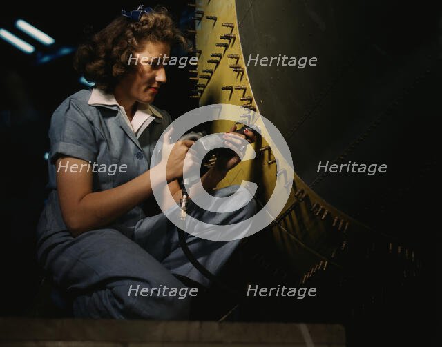 Riveter at work on Consolidated bomber, Consolidated Aircraft Corp., Fort Worth, Texas, 1942. Creator: Howard Hollem.