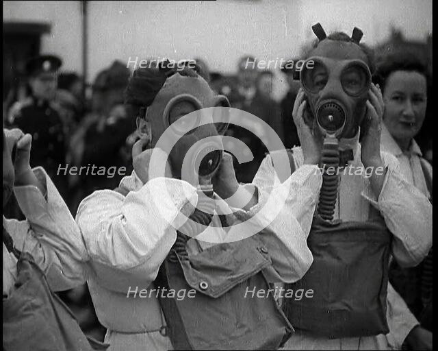 A Close up of Three Female Civil Defence Volunteers in White Boiler Suits Putting on Gas..., 1938. Creator: British Pathe Ltd.