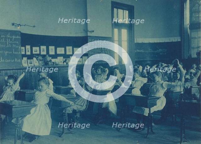 Children doing calisthenics while sitting at their desks in a classroom..., Washington, DC, (1899?). Creator: Frances Benjamin Johnston.