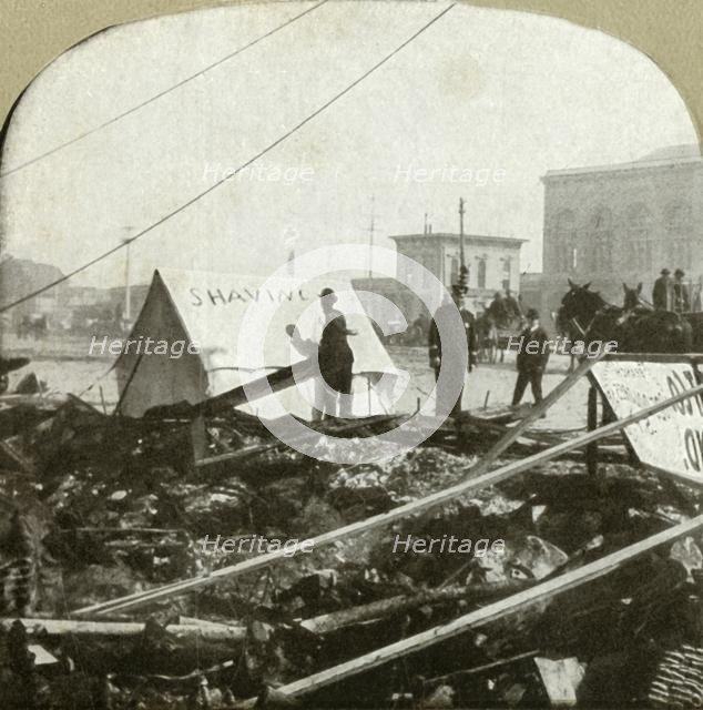 'True grit - Barber painting sign on tent stretched on sidewalk of former place', 1906.  Creator: Unknown.