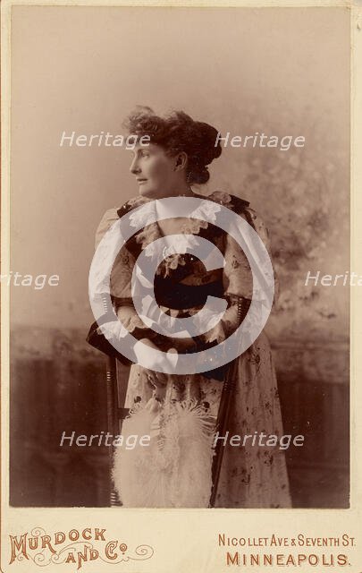 Unidentified woman in profile, leaning on a chair, holding a feather fan, about 1890. Creator: Murdock and Company.
