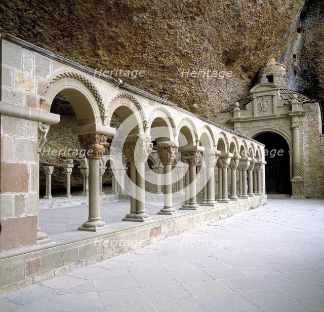 View of the arches and geminated columns of the cloister by the rocks of the Benedictine monaster…