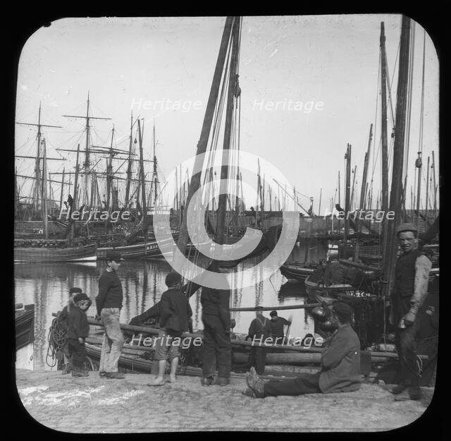 Men and boys with sailing boats in port, unknown location, c1900s. Creator: Robert Augustus Henry L'Estrange.