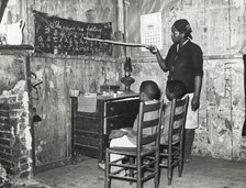 Negro mother teaching children numbers and alphabet in home of sharecropper..., Jan 1939. Creators: Farm Security Administration, Russell Lee.