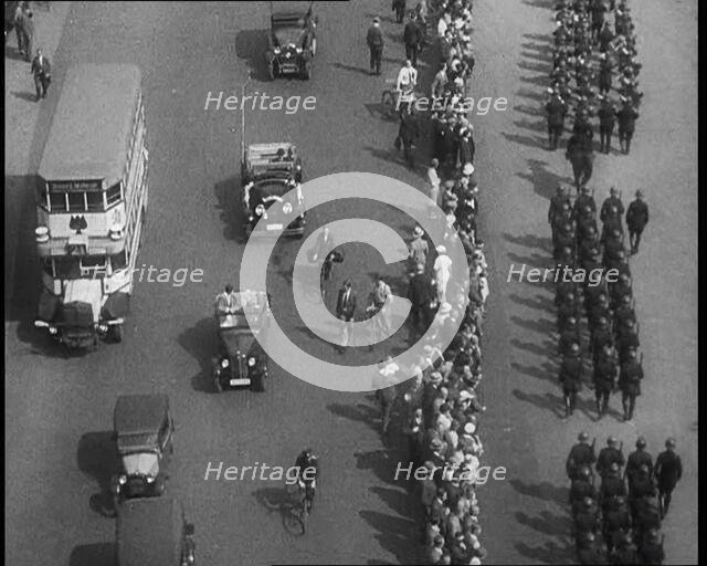 Aerial Shot of Soldiers Marching Down the Road in Front of a Crowd, 1933. Creator: British Pathe Ltd.