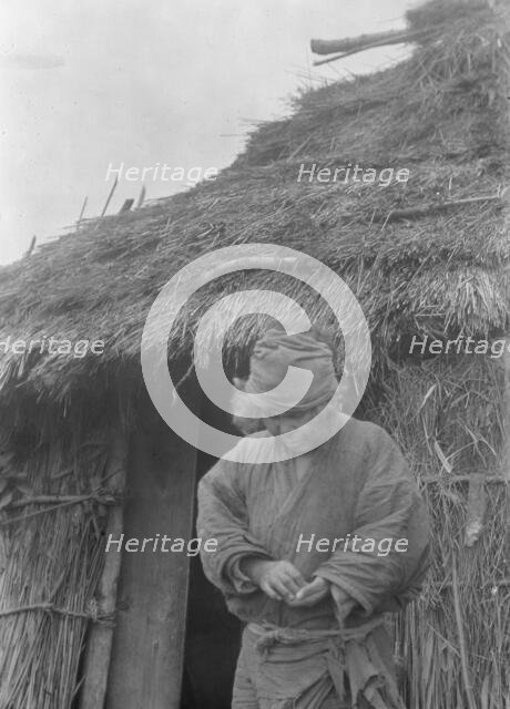 Ainu woman outside a hut, 1908. Creator: Arnold Genthe.