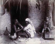Two Indian men crouching; one is cutting the other's hair, while a girl sits.., c1890s.  Creator: Unknown.