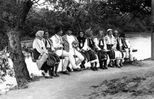 Group of people seated on a bench, Bistrita Valley, Moldavia, north-east Romania, c1920-c1945. Artist: Adolph Chevalier