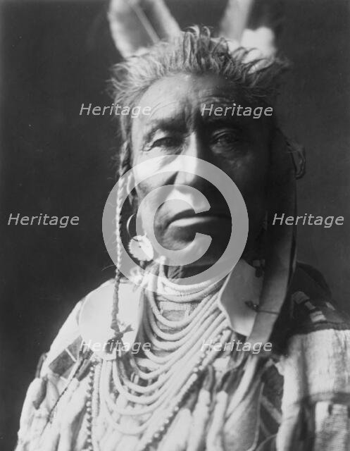 Fish Shows, an Apsaroke Indian, head-and-shoulders portrait, facing front, pompadour..., c1908. Creator: Edward Sheriff Curtis.