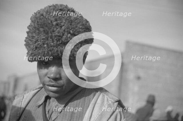 Negro with a fur cap, a flood refugee in the camp at Forrest City, Arkansas, 1937. Creator: Walker Evans.