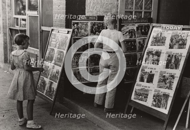 Children looking at posters in front of movie, Saturday, Steele, Missouri,  1938-08. Creator: Russell Lee.
