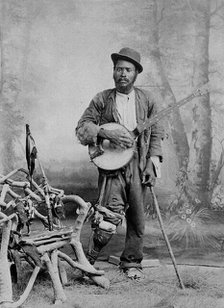 A black banjo player with a wooden leg, c1865. Creator: Unknown.