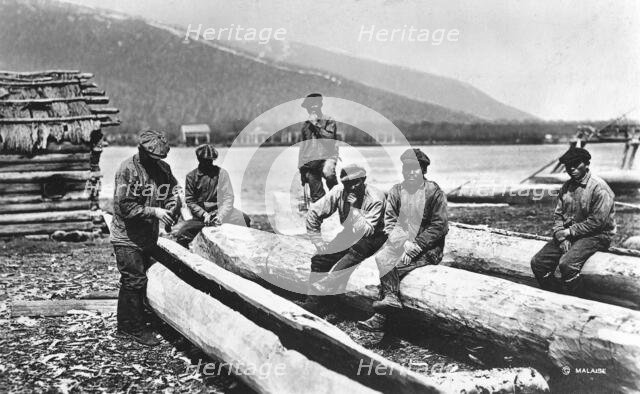 Kamchadals on the river bank near the baht and logs prepared for hollowing out the baht, 1922-1923. Creator: Rene Malaise.