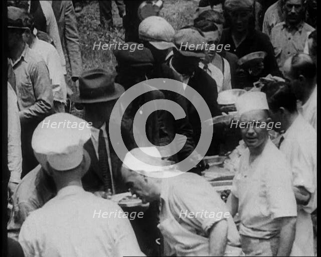 American Civilians Serving Meals for a Large Crowd on a Queue Outdoors, 1930. Creator: British Pathe Ltd.