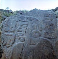 Detail of a sculptural relief on a rock representing a man with a large earring, at his left the …