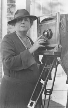 Frances Benjamin Johnston, 1864-1952, half length, facing front, adjusting lens..., c1936. Creator: Frances Benjamin Johnston.