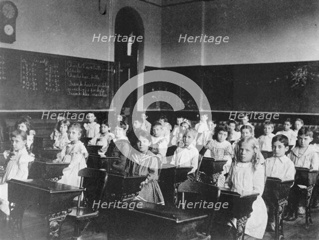 Girls and boys seated at desks in classroom, Washington, D.C., (1899?). Creator: Frances Benjamin Johnston.
