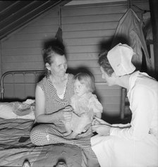 Resident nurse interviews mother and examines sick baby, FSA camp, Farmersville, CA, 1939. Creator: Dorothea Lange.